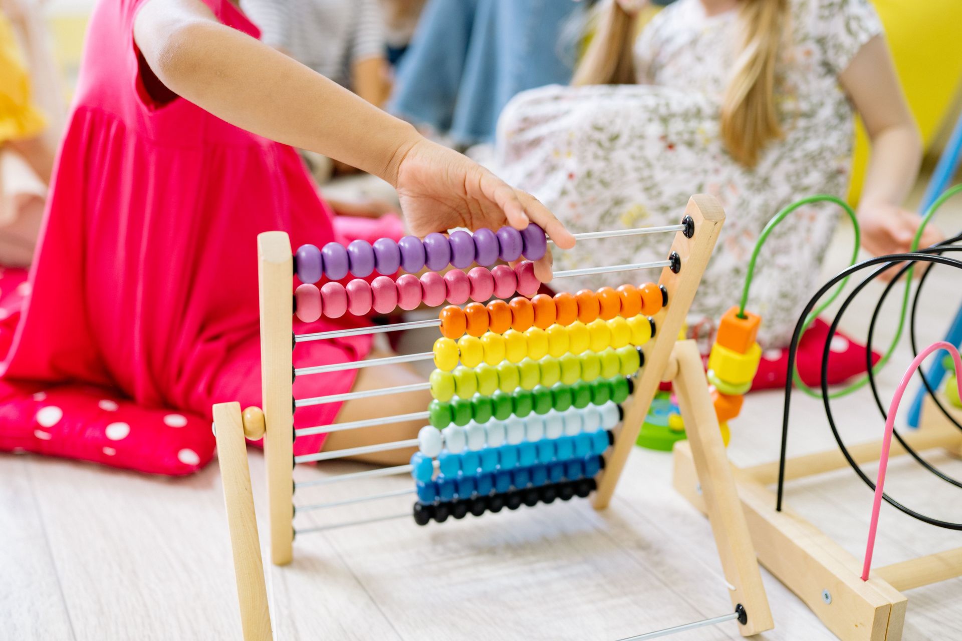 Children actively learning with a colorful abacus in a preschool setting, enhancing educational fun.