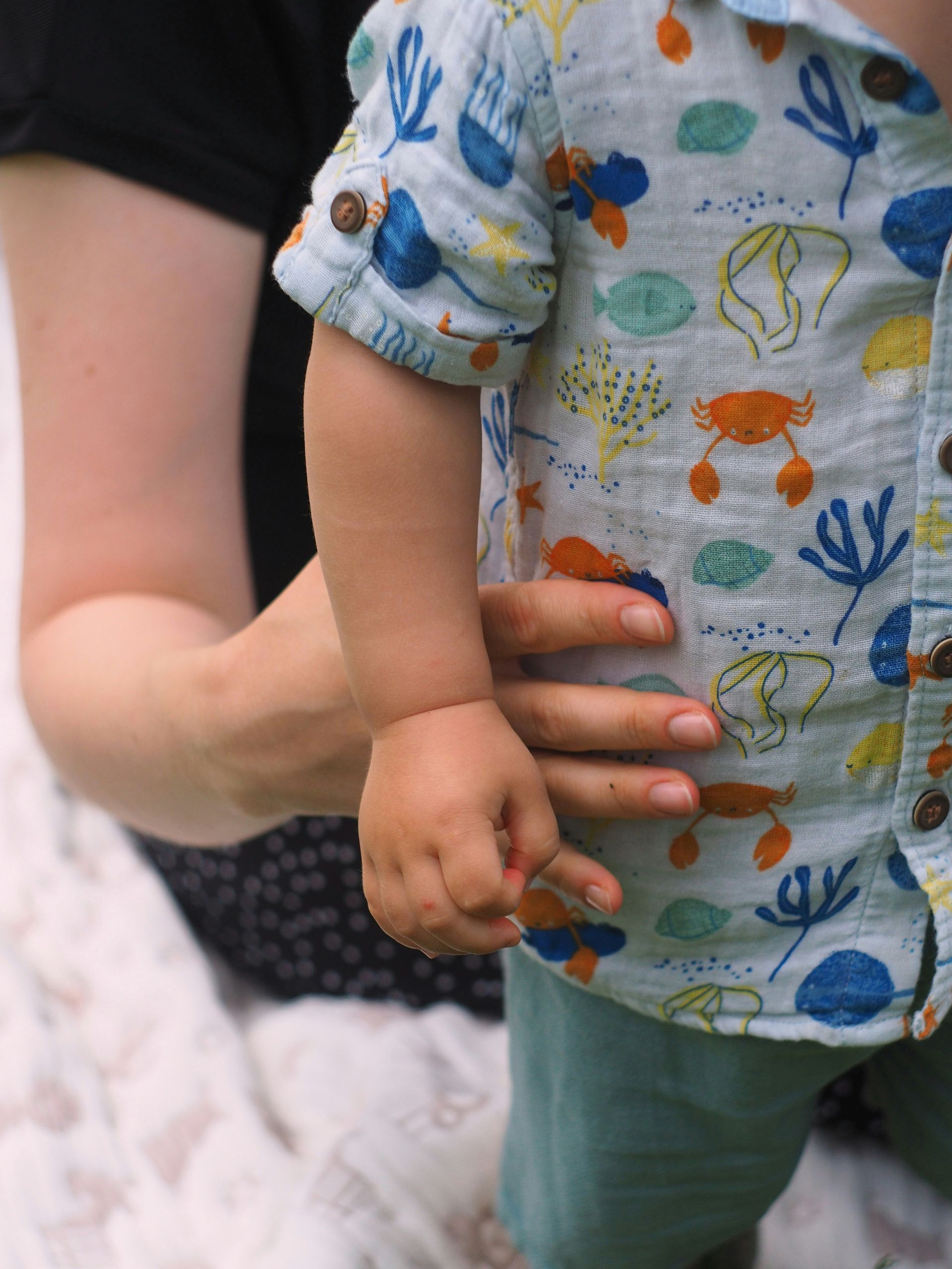 A small child is holding his mother's hand
